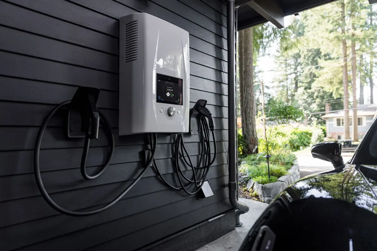 Cargador de auto eléctrico y estación de energía en el muro de una cochera, junto a un auto