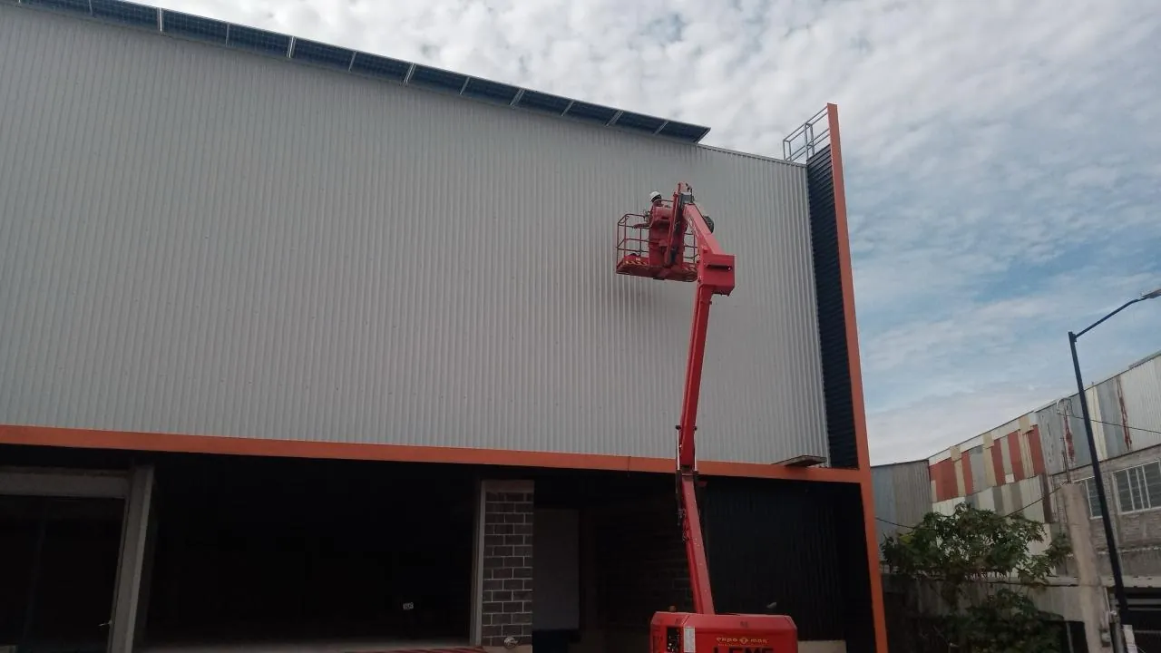 Trabajo en altura con plataforma elevadora en la fachada de una nave industrial